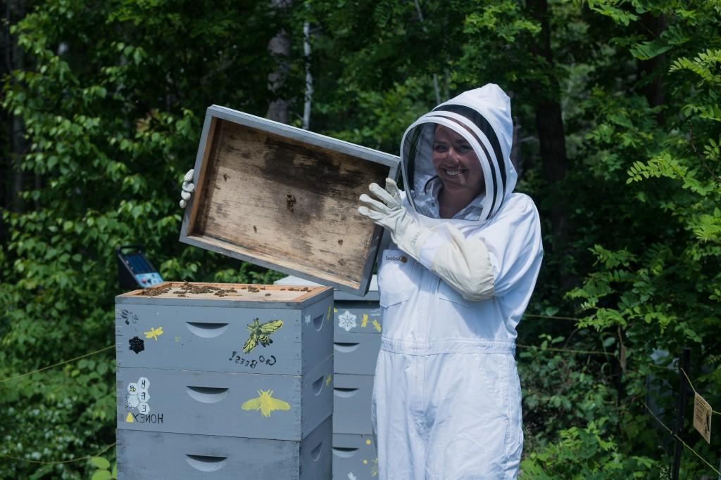 A U N E student beekeeper lifts the lid off a bee hive